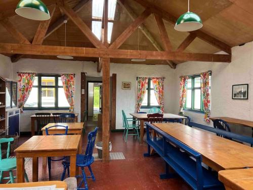 een eetkamer met tafels, stoelen en ramen bij Wicklow Wild Glamping Shepherds Huts at Greenan Maze in Rathdrum
