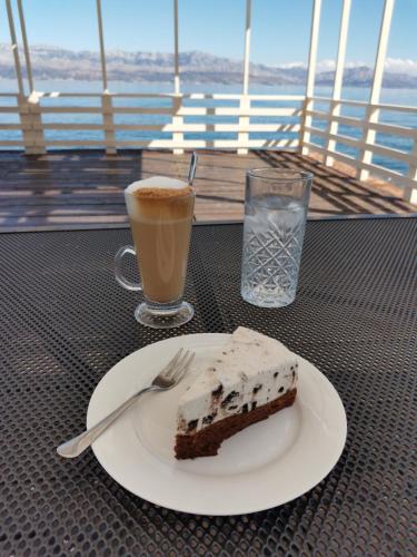 a piece of cake on a plate with a fork and a drink at Taverna & Rooms in Sutivan