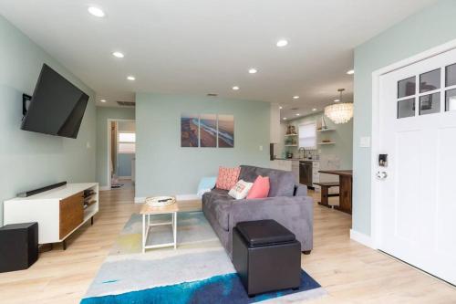 a living room with a gray couch and a tv at Beach House In The Heart Of PB in San Diego