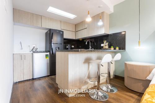 a kitchen with a refrigerator and a counter with stools at Park 42 APARTASUITES in Medellín