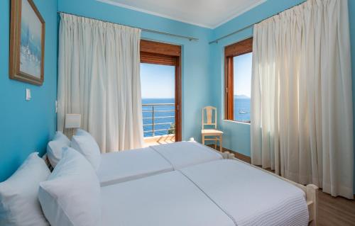 Dormitorio azul con cama y ventana grande en Iris Villas Lefkada - Marine Villa, en Évyiros