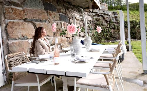 a woman sitting at a white table with pink flowers at Forest house in Ljungskile