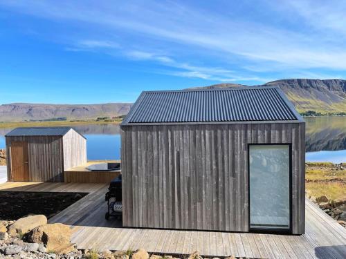 une maison sur un quai à côté d'une masse d'eau dans l'établissement Peaceful Lakeside Cabin, à Reynivellir