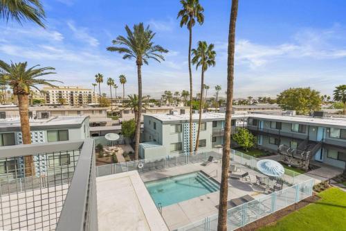 an apartment with a swimming pool and palm trees at Walkable OTS, Heated Poolside Mid Century Condo in Scottsdale