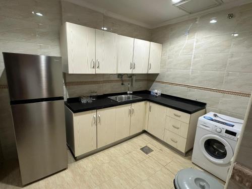 eine Küche mit einem Kühlschrank aus Edelstahl sowie einer Waschmaschine und einem Trockner in der Unterkunft Luxurious apartment in Mahboula in Kuwait