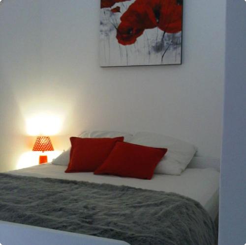 - une chambre avec un lit doté d'oreillers rouges et d'une photo dans l'établissement Appartement Sanary Sur Mer., à Sanary-sur-Mer