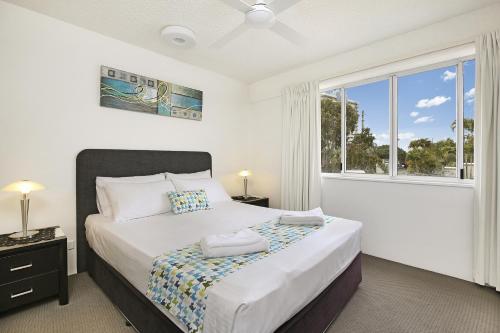 a bedroom with a bed and a large window at Beachside Mooloolaba in Mooloolaba