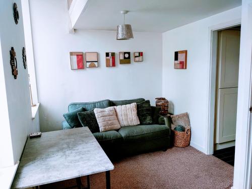 a living room with a green couch and a table at Butterfly Apartment in Ossett