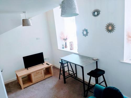 a living room with a table and a television at Butterfly Apartment in Ossett
