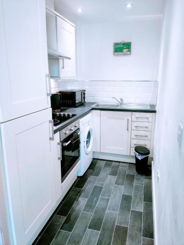 a kitchen with white cabinets and a washer at Butterfly Apartment in Ossett