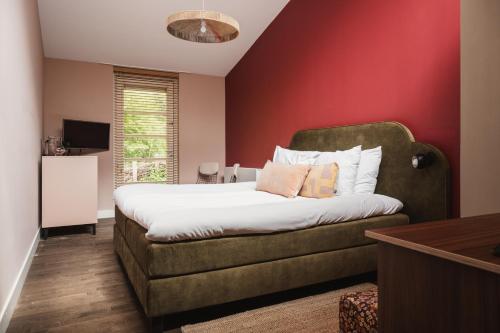 a bedroom with a bed with a couch and a red wall at Zoomers aan het Bos in Castricum