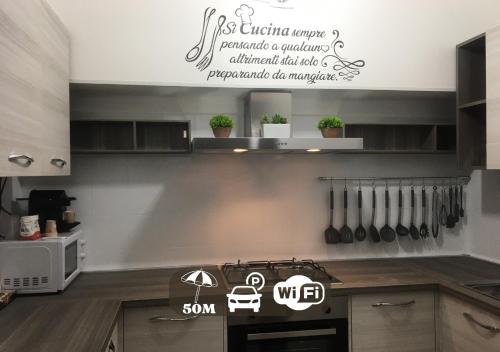 a kitchen with a stove with a sign on the wall at HoliHome_La Sirena 50m dal Mare in Tortoreto Lido