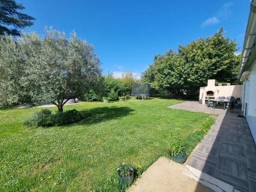 une cour arrière avec une pelouse avec une table de pique-nique et des arbres dans l'établissement chambres d'hôtes Le Boisseau, à Saint-Michel-de-Montaigne