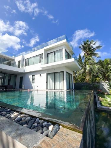 a house with a swimming pool in front of it at Stunning Beachfront Villa for a Perfect Getaway in Riambel