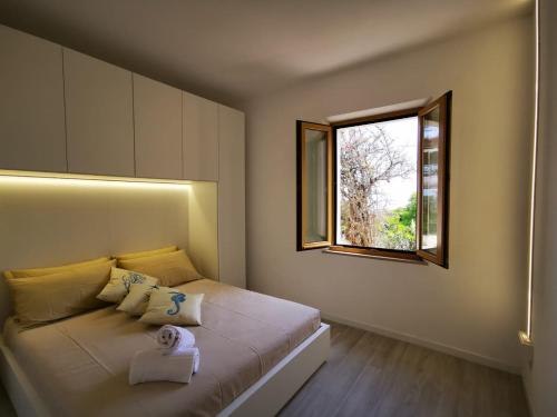 1 dormitorio con 1 cama grande y ventana en casa panoramica bouganville, en SantʼAndrea