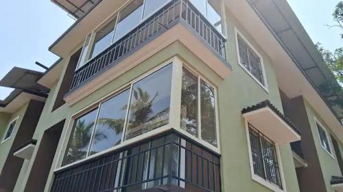 una casa con balcone e molte finestre di Halcyon - Tropical Elegance - 2BHK a Moira