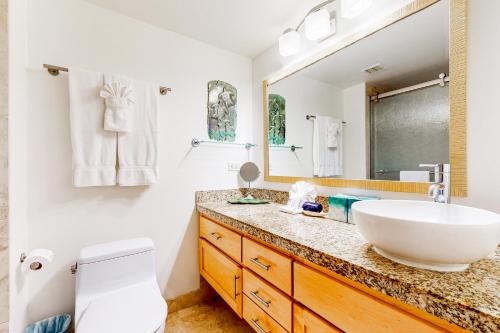 une salle de bain avec un lavabo et un grand miroir dans l'établissement Kahana Reef 211, à Kahana