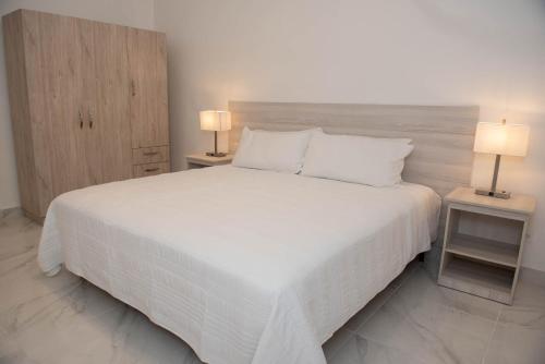een slaapkamer met een groot wit bed met 2 lampen bij CASA BIANCA Bella Vista in Panama-Stad