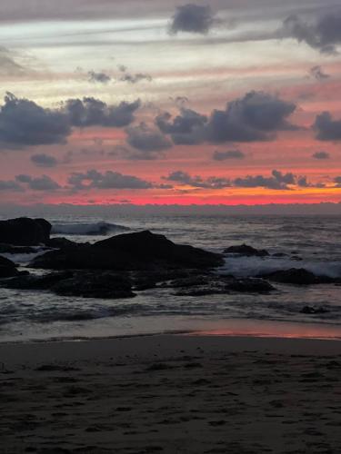 a sunset on the beach with rocks in the water at Casa Mari Black Stallion in Tamarindo