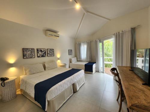 a bedroom with a bed and a desk and a television at Byblos Pousada in Búzios