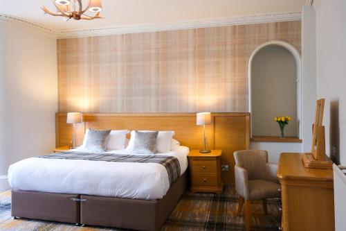 a bedroom with a bed and a desk and a chair at Glen Mhor Hotel at Uile-bheist 'Brewstillery' in Inverness