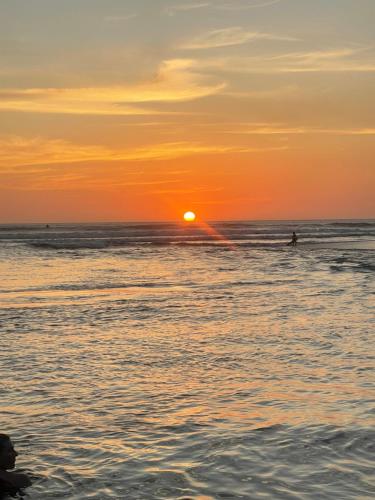 a person playing in the ocean at sunset at Casa Mari Black Stallion in Tamarindo