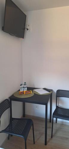 uma mesa com duas cadeiras e uma televisão na parede em Pokoje u Lucyny 