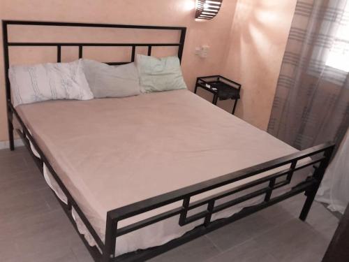 a bed with a black frame and white sheets and pillows at Logement familial et groupe in Sali Nianiaral