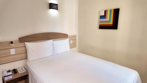 a bedroom with a bed with white sheets and a painting at Larison Executive by Easy Hotéis in Porto Velho