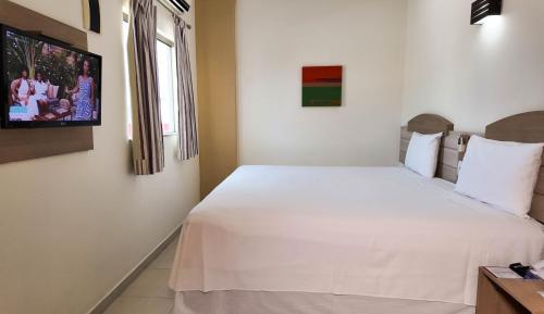 a bedroom with a white bed and a television at Larison Executive by Easy Hotéis in Porto Velho