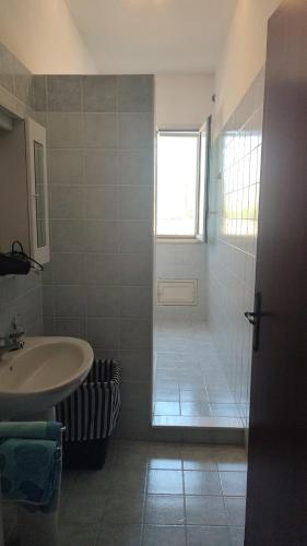 La salle de bains est pourvue d'un lavabo, d'une douche et d'une fenêtre. dans l'établissement Balestrate holiday home 70 Mq, à Balestrate