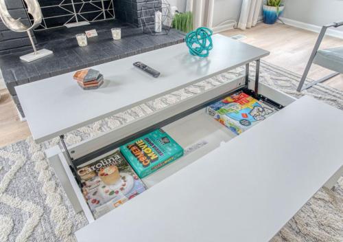a white table in a living room with books on it at Stylish Home Near Uptown, UNC, and More! in Charlotte