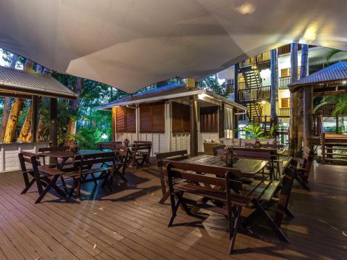 un restaurante con mesas de madera y sillas en una terraza en The Reef Retreat Palm Cove en Palm Cove