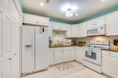 a kitchen with white cabinets and a refrigerator at Cozy Goose Creek Escape with Patio and Grill in Goose Creek