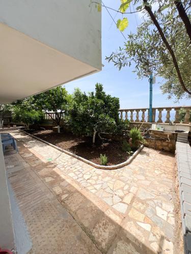 a patio with a stone walkway and a fence at Petra Oliva Apartment in Dhërmi