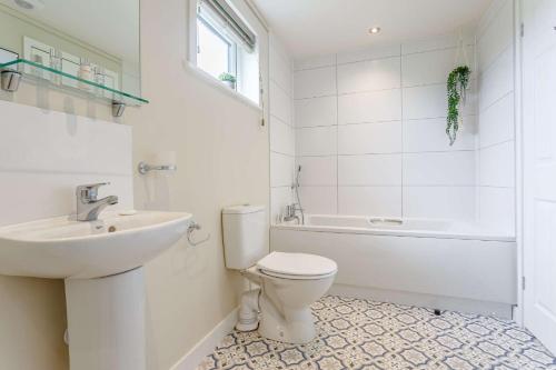 Baño blanco con aseo y lavamanos en Duet Lodge 32 en Kingham