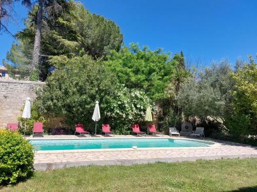 une piscine avec chaises et parasols dans une cour dans l'établissement Mas Fontclaire - Sommières, à Sommières