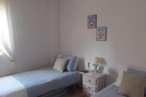 a bedroom with two beds and a nightstand and a window at Casa Atalanta - huis met zwembad in Albatros 2 in Mar de Cristal