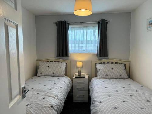 two beds in a small bedroom with a window at 21 M&T Chalets ,2 bed chalet Florida holiday park , Hemsby in Hemsby