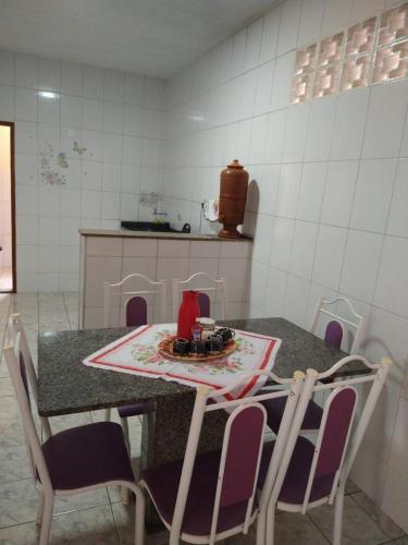 eine Küche mit einem Tisch mit Stühlen, einem Tisch und einer Theke in der Unterkunft CASA DA LÉIA in Caparaó Velho