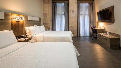 a hotel room with two beds and a desk at Holiday Inn Express Morelia Centro Historico in Morelia