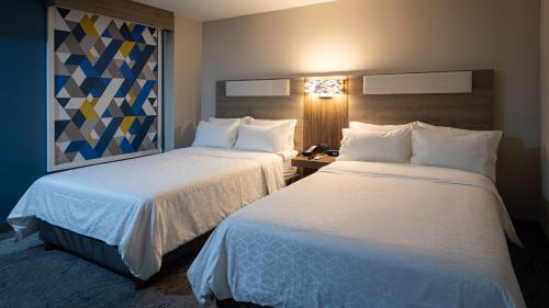 two beds in a hotel room with white sheets at Holiday Inn Express Morelia Centro Historico in Morelia