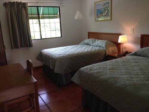 a hotel room with two beds and a window at Hotel Brandts Los Robles de San Juan in Managua