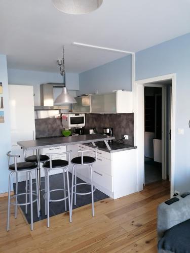 une cuisine avec des armoires blanches et des tabourets de bar dans l'établissement Les Voiliers au Touquet-Paris-Plage, à Le Touquet-Paris-Plage