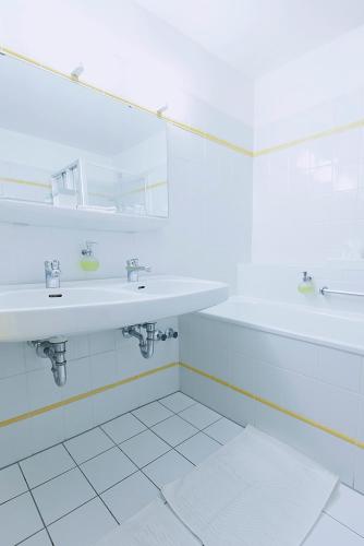 a white bathroom with two sinks and a mirror at Romantik Hotel Alte Vogtei in Hamm