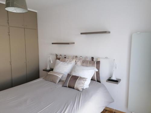 une chambre avec un lit avec des draps blancs et des oreillers dans l'établissement Les Voiliers au Touquet-Paris-Plage, à Le Touquet-Paris-Plage