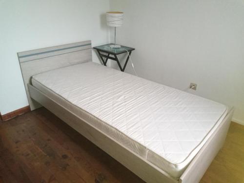 - un lit blanc dans une chambre avec une table de chevet dans l'établissement Maison de campagne, à Thiaucourt