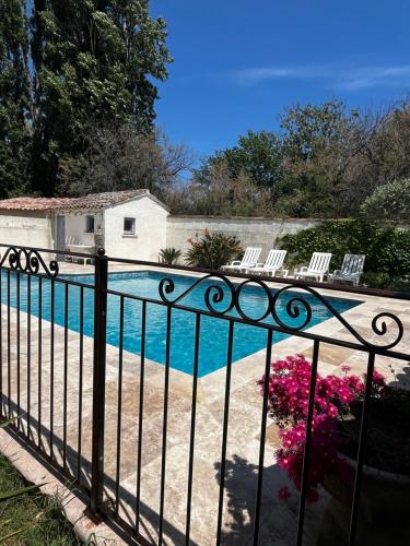 une piscine derrière une clôture avec des chaises et des fleurs dans l'établissement La Maison Brennus , Piscine, 15 Min des Plages, à Béziers