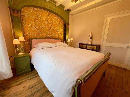 a bedroom with a large bed with a green headboard at Château le Withof in Bourbourg