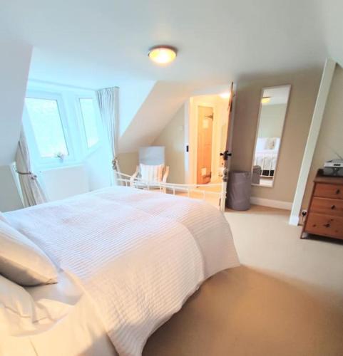 a bedroom with a large white bed and a staircase at Squirrels' Drey in Innerleithen